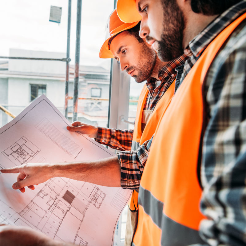 thoughtful builders working with blueprint at construction site